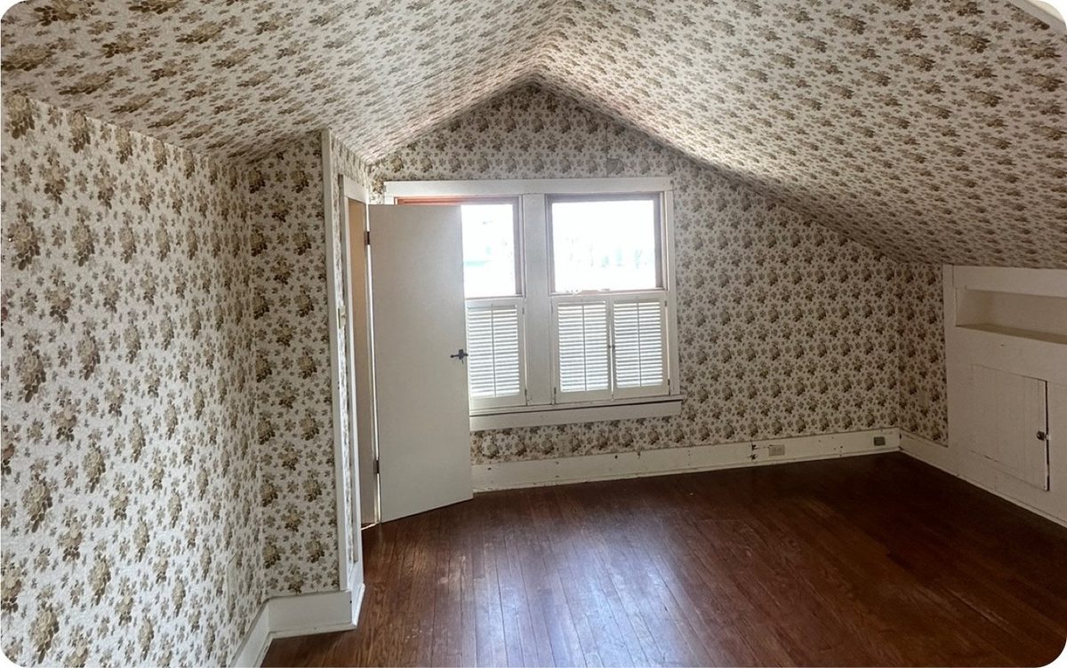 Attic before: dated wallpaper and worn floors