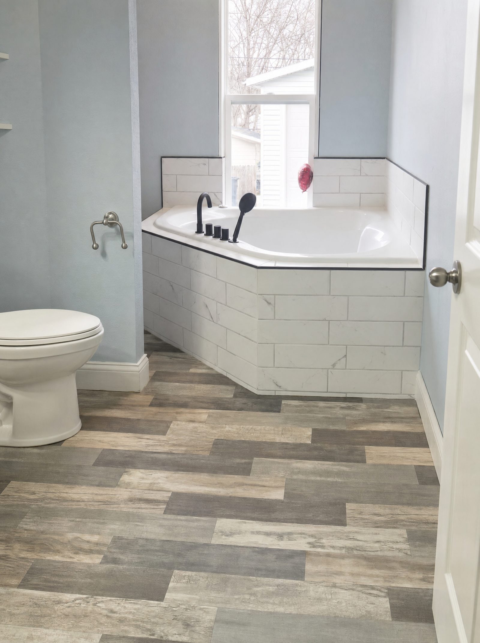 Remodeled bathroom with corner tub, subway tile and new plank flooring