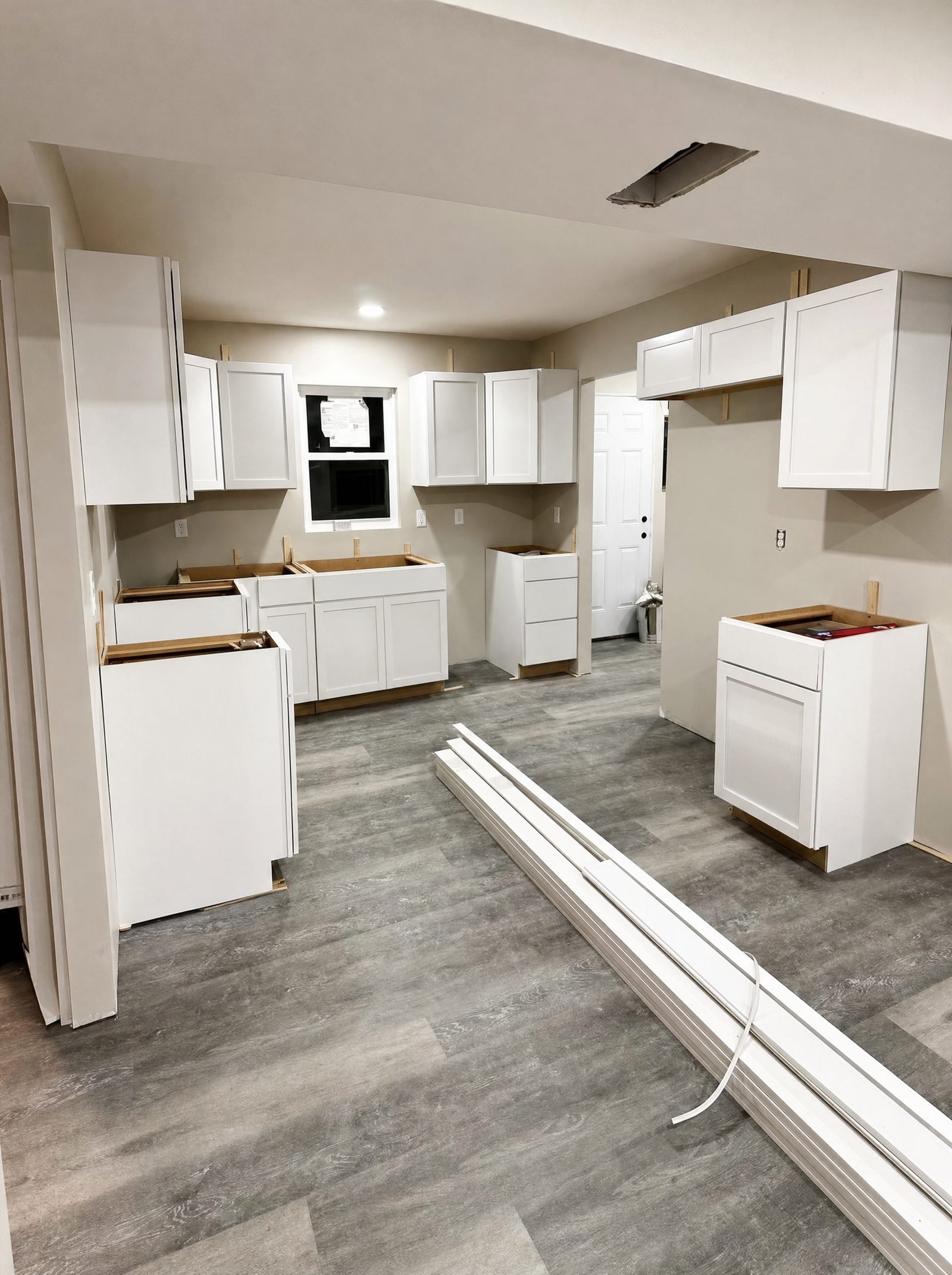 Kitchen with new white cabinets and plank flooring